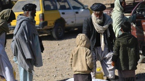 People collect food aid distributed by the Red Cross in Kandahar on December 15, 2021. (Photo by ...