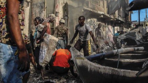 TOPSHOT - Men pick up aluminum pieces at the site where a tanker truck exploded in Cap-Haitien, ...