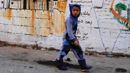 A child walks past a mural showing the Palestinian national flag inside the Burj al-Shemali refugee ...