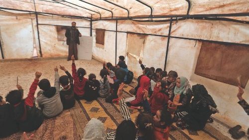 A volunteer teacher teaches students in make-shift classrooms at a camp for the displaced by the ...