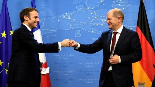 France's President Emmanuel Macron (L) and Germany's Chancellor Olaf Scholz bump fists after holding ...