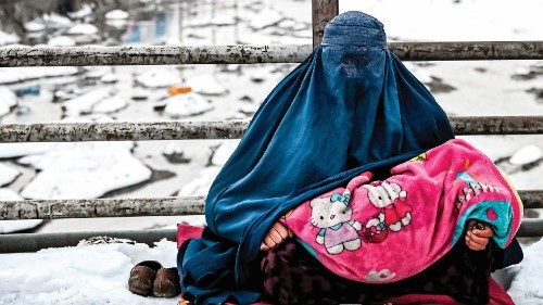 TOPSHOT - A burqa-clad Afghan woman sits with a child on her lap as she seeks alms from passers-by ...