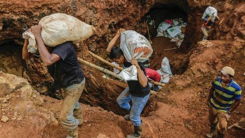 Miners carry sacks with rocks to be crushed, in order to extract gold, in the 'IRON' gold mine some ...