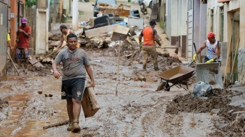 Residents clean the streets after floods hit the area with pouring rains in Raposos, in Minas Gerais ...