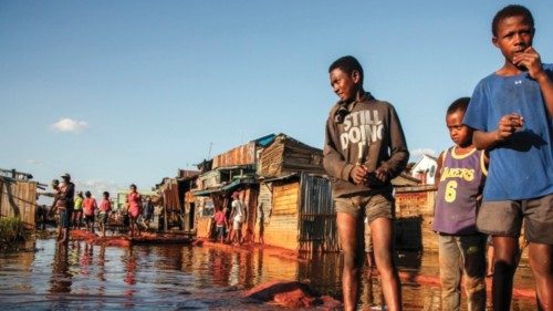 Children and residents stand in a flooded area of the 67-hectare Ankasina neighbourhood in ...