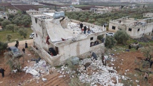 epa09724582 An aerial picture taken by a drone shows people inspecting a damaged building after an ...