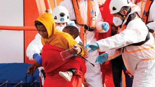 epa09716126 A migrant and her baby are helped by several rescue members at Arguineguin port in Gran ...