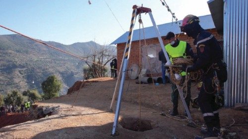 Rescuers stand near the whole of a well into which a five-year-old boy fell in the northern hill ...