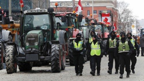 Police officers walk past parked tractors, as truckers and supporters continue to protest ...