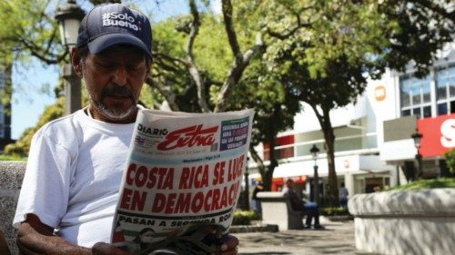 A man reads a newspaper with a cover story on the preliminary results of Costa Rica's first-round ...
