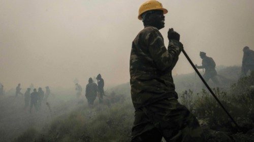 A warden of Kenya Wildlife Service reacts as he extinguishes the edge of a burning area to stop the ...