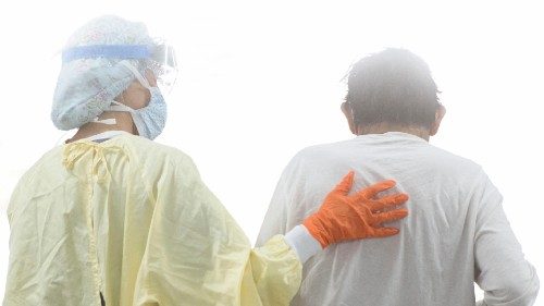 A nurse supports a patient as they walk in the Covid-19 alternative care site, built into a parking ...