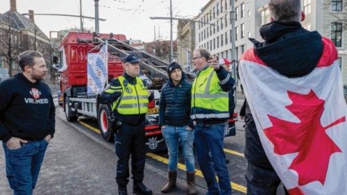 Police officers talk to protestors wearing a Canadian flag at the entrance of the Binnenhof during a ...