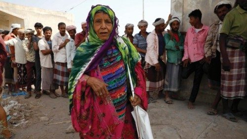 epa09750730 A Yemeni woman passes people waiting in queue to check their names on the lists of ...