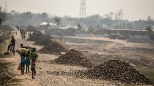 Children pass piles of stone ready for the re-paving on a road in Bihar, India.