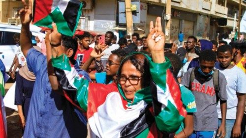 A Sudanese demonstrator dressed in her country's national colours flashes the V for victory sign ...