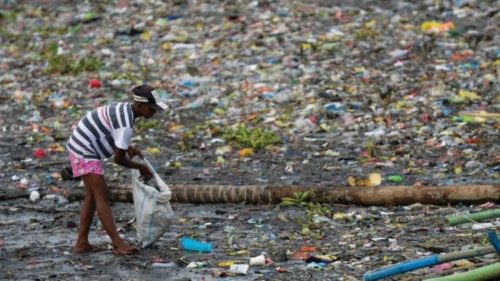 FILE PHOTO: A woman picks up plastic cups along the riverbank of Pasig river, in Manila, ...