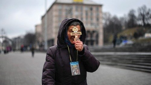 A religious woman holds a cross as she prays on Independence square in Kyiv in the morning of ...
