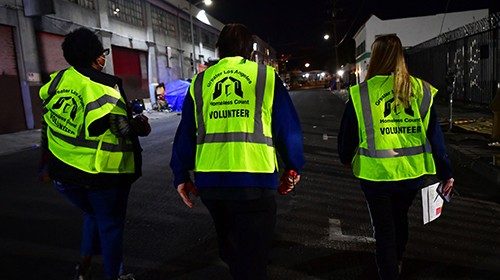 Volunteers Kimberly Briggs (L), Mike Murase (C), Jessica Margraf walk the streets of downtown Los ...