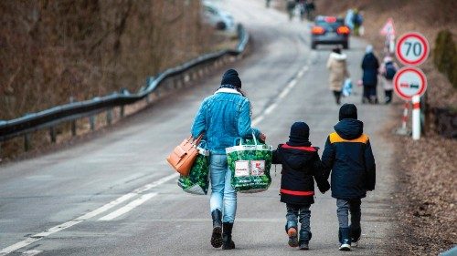A woman with two children and carrying bags walk on a street to leave Ukraine after crossing the ...