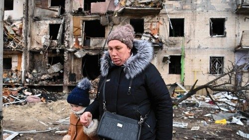 TOPSHOT - A woman with a child walks in front of a damaged residential building at Koshytsa Street, ... TOPSHOT - A woman with a child walks in front of a damaged residential building at Koshytsa Street, ...