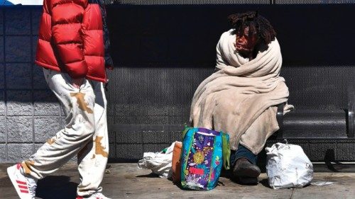 (FILES) In this file photo taken on February 24, 2022, a pedestrian walks past a homeless on the ...