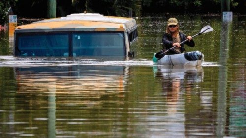 TOPSHOT - A man paddles his kayak next to a submerged bus on a flooded street in the town of Milton ...