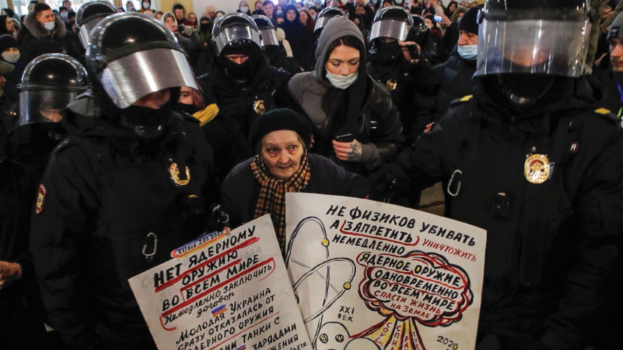 Law enforcement officers escort an elderly woman during an anti-war protest against Russia's ...