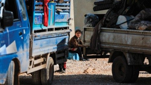 An internally displaced Syrian child sits among trucks loaded with peosonal belongings at a camp, ...