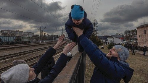 epa09801377 Oleg (R), who decided to remain in Irpin, passes his son Maksim over a fence to his wife ...