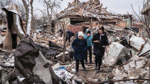 Women walk among remains of residential buildings destroyed by shelling, as Russia's invasion of ...