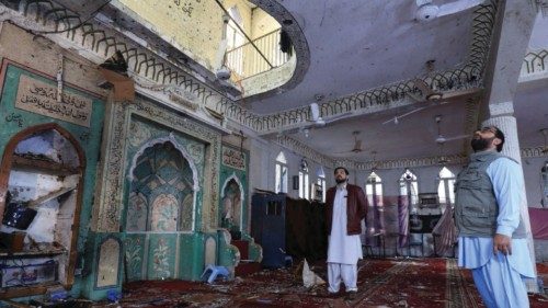 People stand amid the damages at the prayer hall after a bomb blast inside a mosque during Friday ...