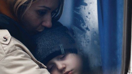 A woman and her son are seen through a bus window as they arrive at a temporary accommodation ...