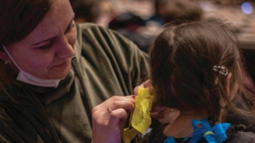 epa09808075 A woman ties ribbons in Ukrainian national flag colors in a girl's hair as people wait ... epa09808075 A woman ties ribbons in Ukrainian national flag colors in a girl's hair as people wait ...