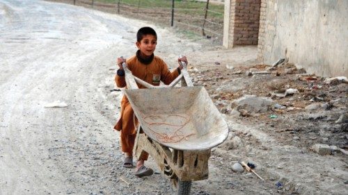 A boy pushes a wheelbarrow along a street in Kandahar on March 5, 2022. (Photo by Javed TANVEER / ...