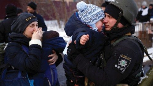 A police officer says goodbye to his son as his family flees from advancing Russian troops as ...