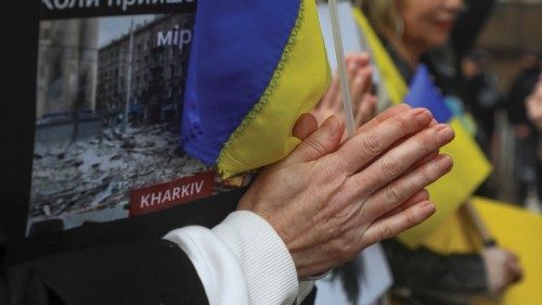 A Ukrainian living in Lebanon gestures for prayer while holding the Ukrainian flag during a protest ...