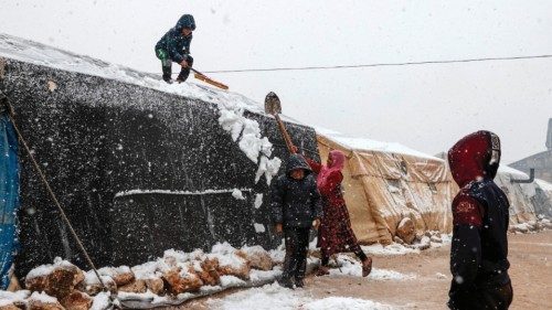 People clear the snow from the roof of a tent at a camp for internally displaced Syrians, near the ...