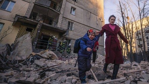 A woman with a child evacuates from a residential building damaged by shelling, as Russia's attack ...