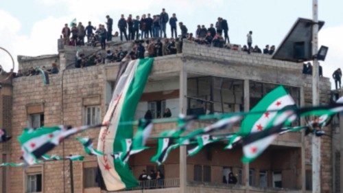 Syrians lift flags during a rally marking 11 years since the start of an anti-regime uprising in ...