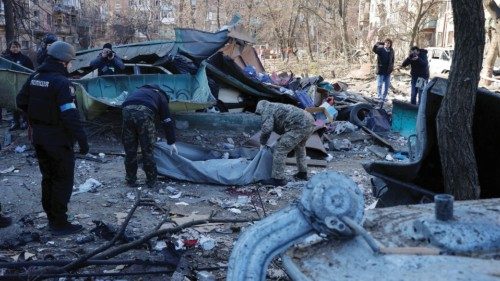 Rescue workers move the body of a person who was killed when a shell hit a residential building, as ...