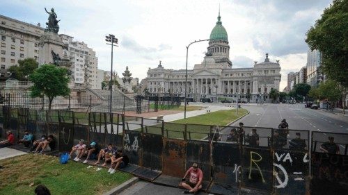 TOPSHOT - Police officers guard behind a fence the Argentine Congress while senators discuss the ...