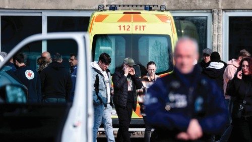 People walk near a gymnasium where witnesses and relatives of victims are received near the site ...