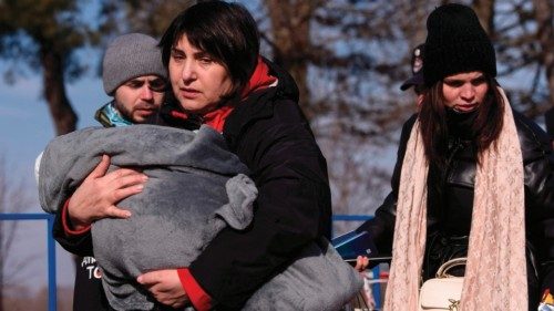 A woman carries a child as Ukrainian refugees cross the Ukrainian-Romanian border in Siret, northern ...