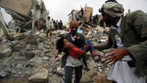 FILE PHOTO: A man carries an injured girl, rescued from the site of a Saudi-led air strike, in ...