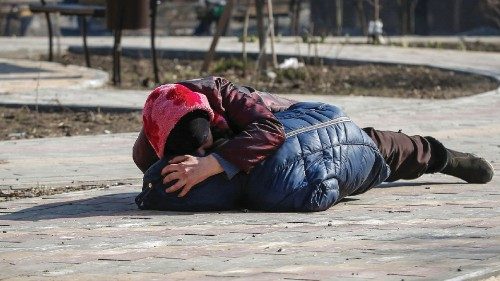 A mother covers her son as they lay on a ground after hearing shelling during Ukraine-Russia ...