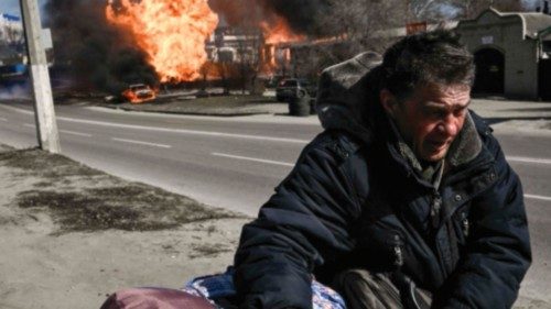A man flees with his belongings as fire engulfs a vehicle and building following artillery fire on ...