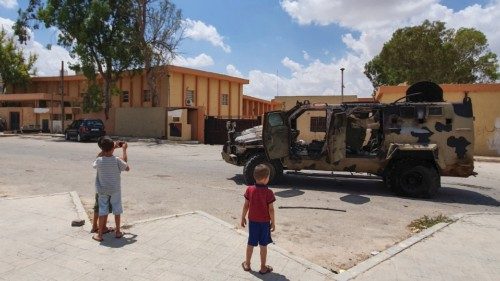 Libyan children take a picture of a burnt vehicle belonging to forces loyal to strongman Khalifa ...