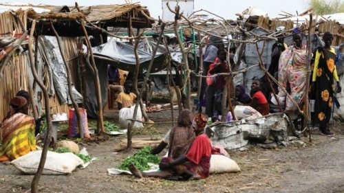 People sit by damaged huts at the inundated Dibba Busin camp for South Sudanese refugees in Sudan's ...