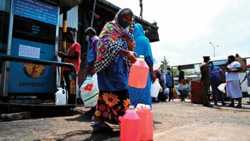 In this picture taken on March 25, 2022, a woman carries a container after buying kerosene for home ...